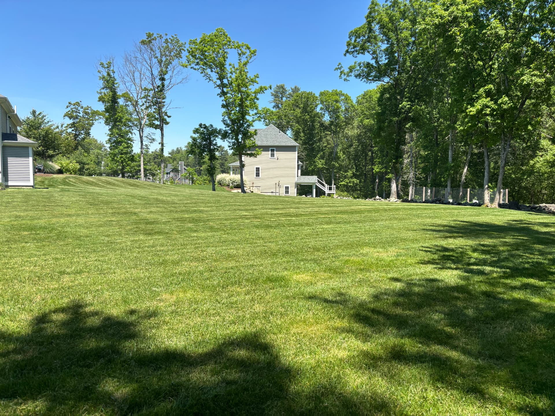 Wide manicured lawn sloping toward a home